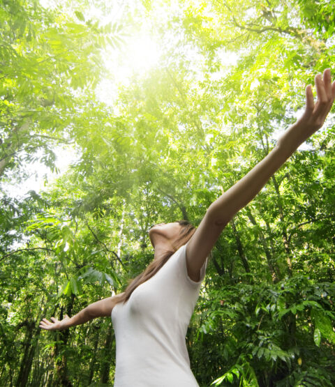 Young woman enjoying nature in green forest